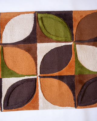 Geometric patterned rug with brown, green, and beige colors on a white background