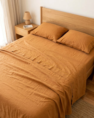 Bed with brown bedding and pillows in a room with a lamp and nightstand.
