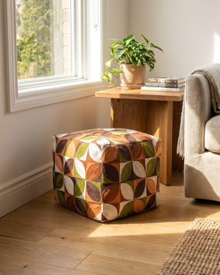 Patterned ottoman in a living room with a couch, table, and plant.