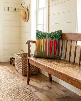 Wooden bench with a colorful pillow in a home interior setting.
